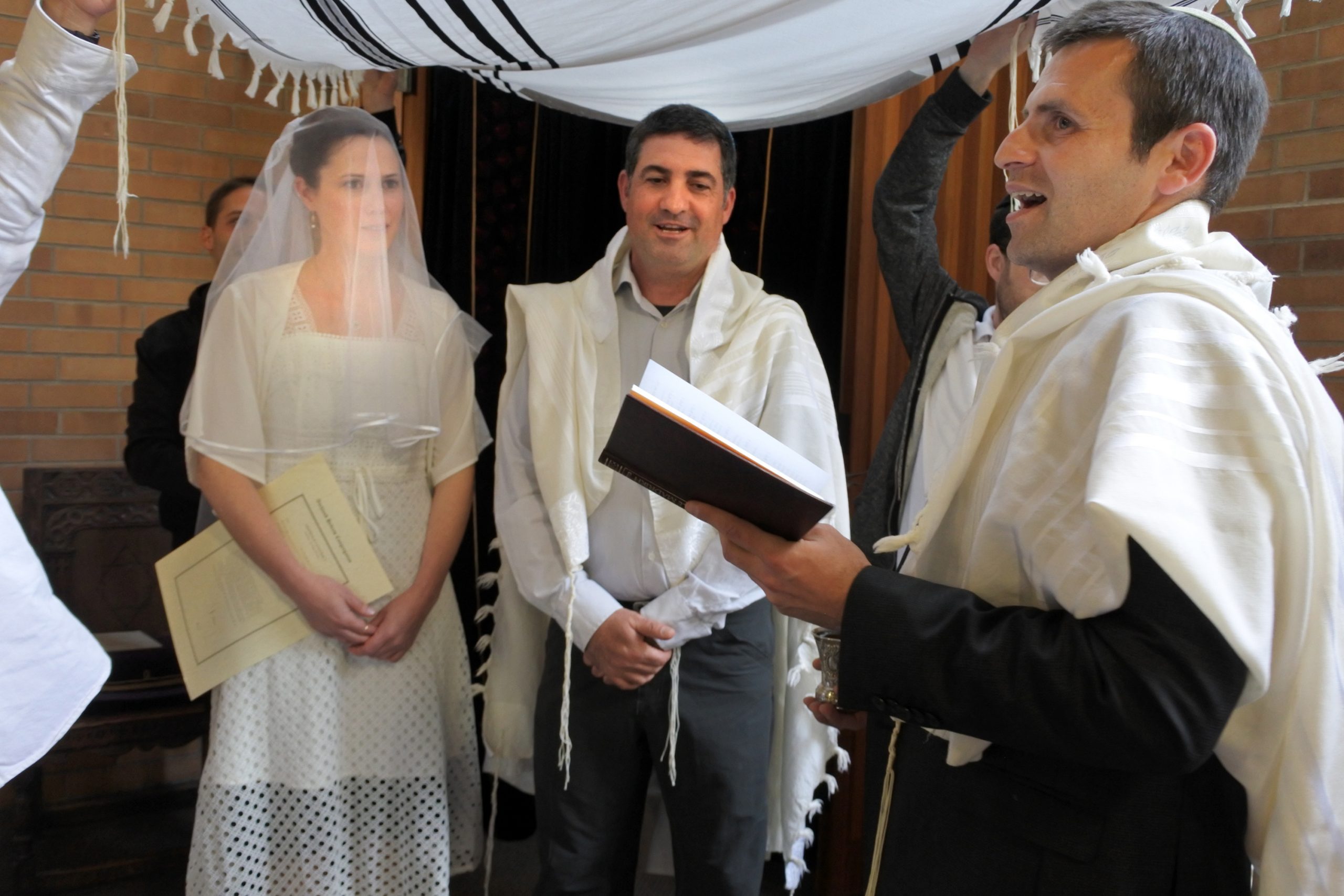 Rabbi blessing Jewish bride and a bridegroom in Jewish wedding ceremony