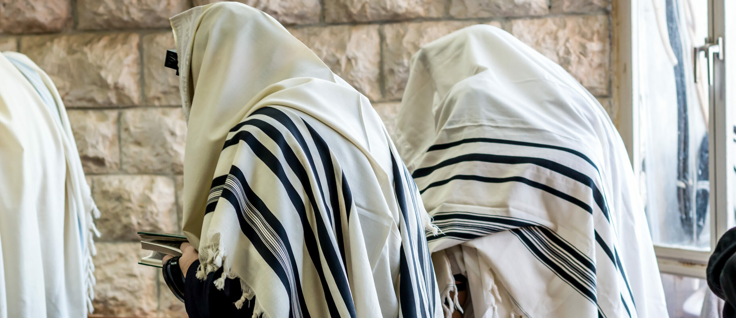 Jewish men praying in a synagogue with tallit