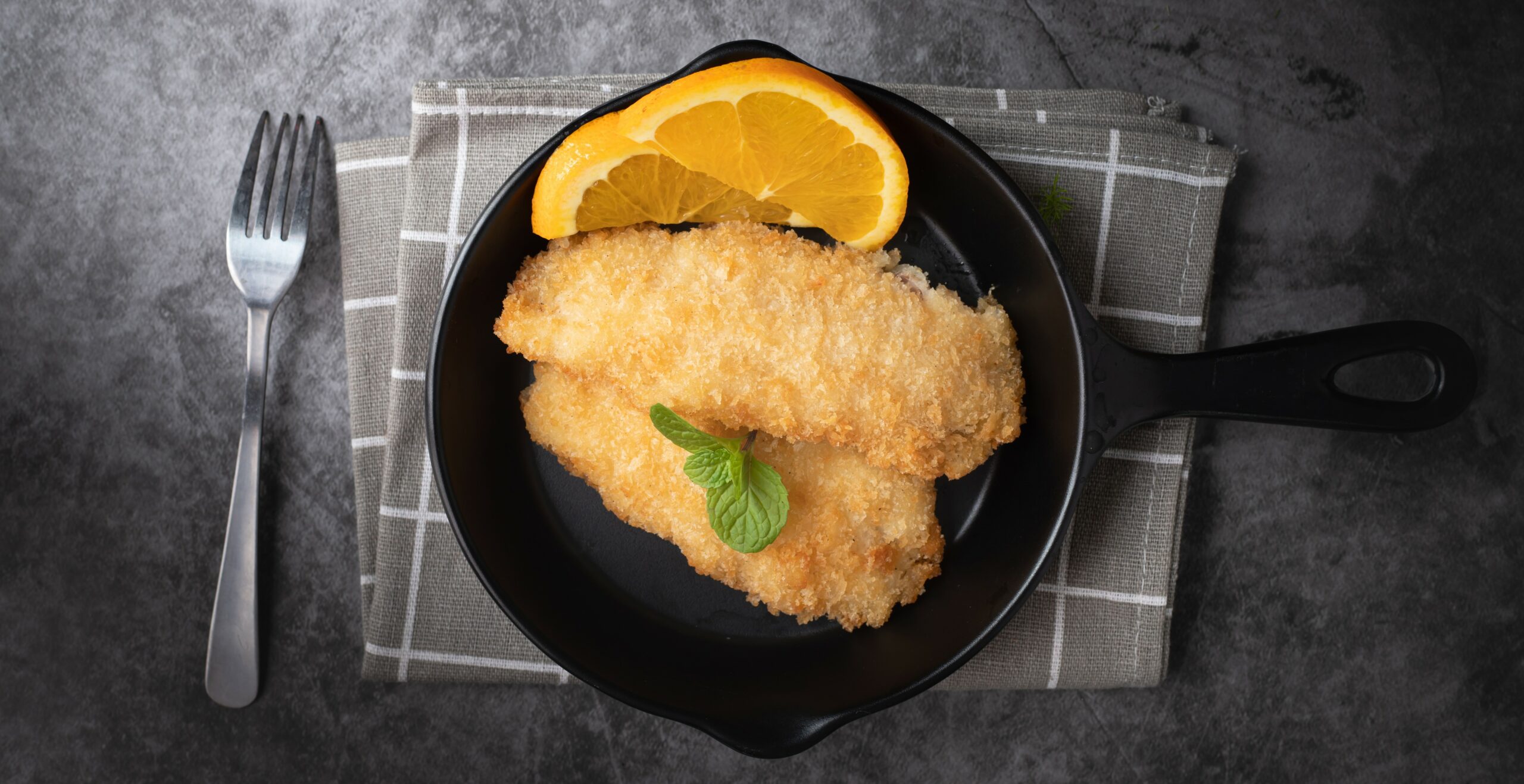 fried fish with lemon on kitchen table.