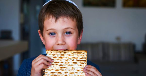 Cute Caucasian Jewish boy holding in his hands and taking a bite